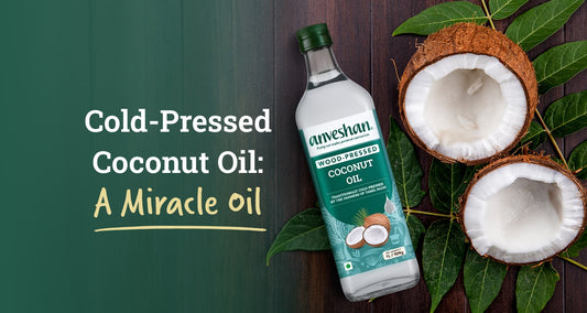 Bottle of Anveshan cold-pressed coconut oil with fresh coconuts on leaves, labeled as a miracle oil